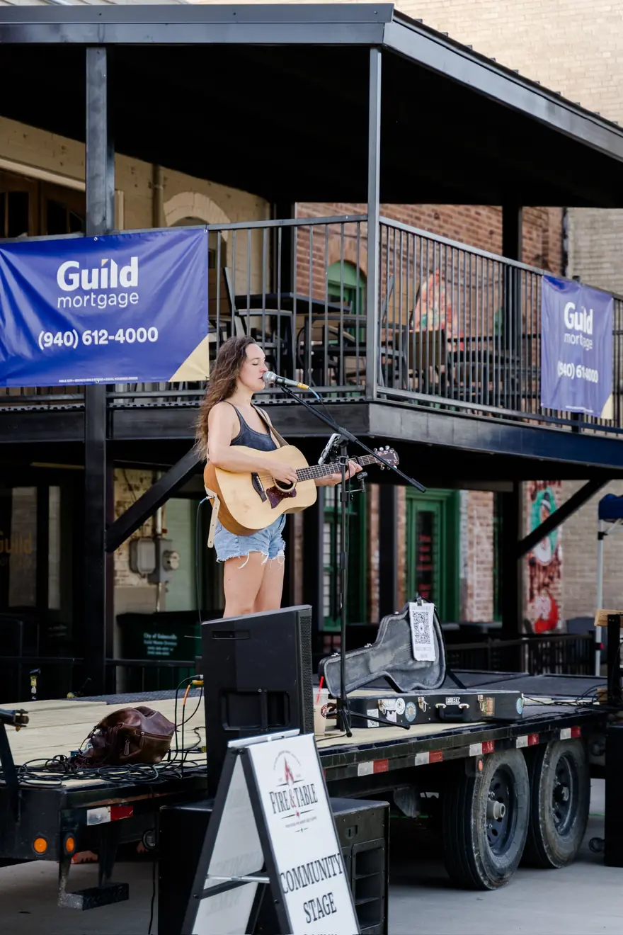 A singer-songwriter performing on the Fire & Table community stage