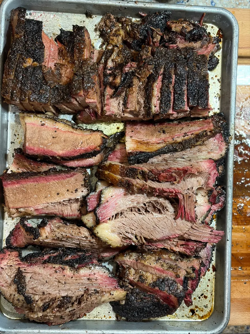 Sliced brisket and beef ribs laid out on a sheet tray