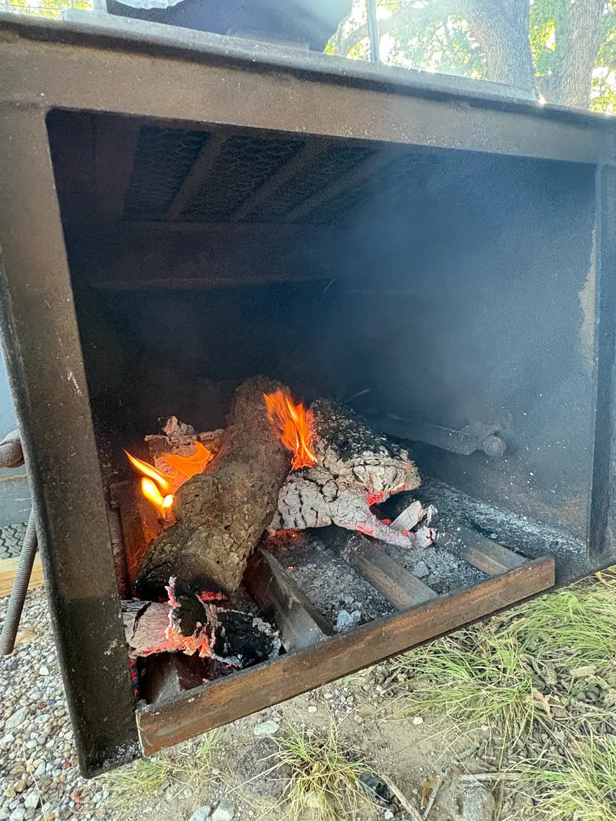 Oak burning down to coals in the firebox of an offset smoker