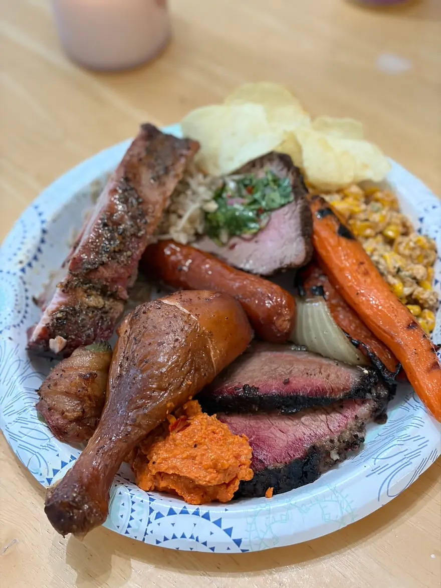 A loaded plate of brisket, sausage, chicken, carrots and street corn