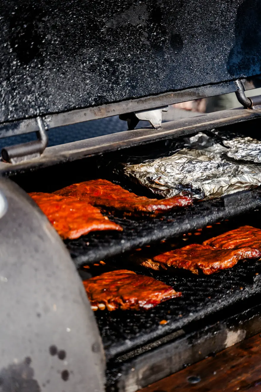 Ribs and foil-wrapped meat on the smoker grate