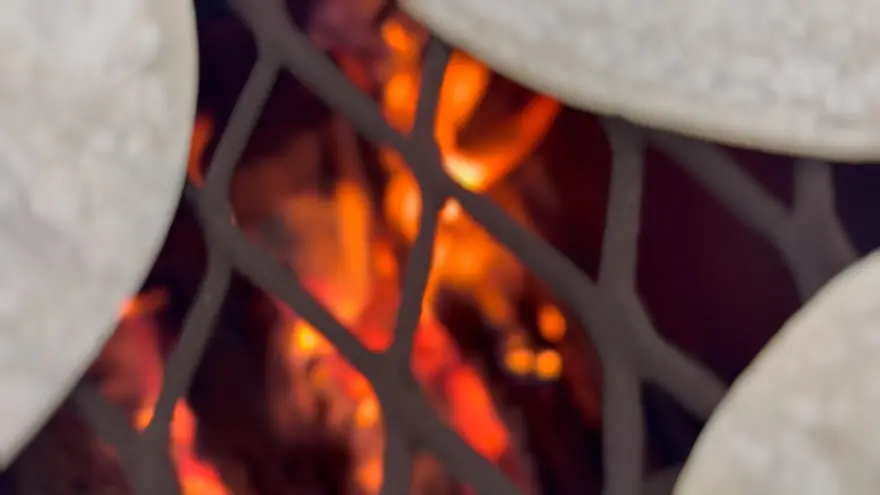 Tortillas warming on a grate over live coals